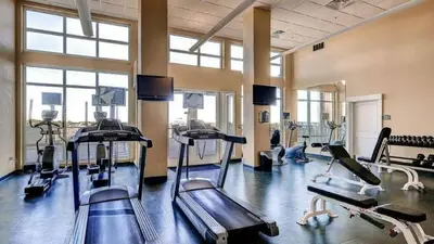 a gym with several tread machines in a room with windows at Grand Panama 1101 in Panama City Beach