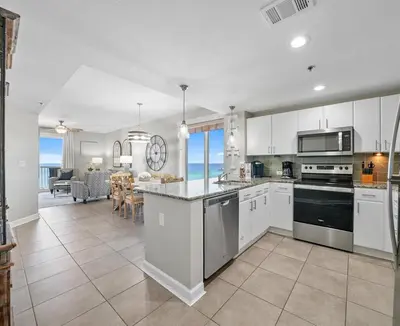 a kitchen with white cabinets and a dining room at Grand Panama 1101 in Panama City Beach