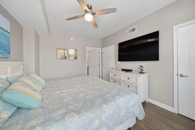 a bedroom with a bed and a flat screen tv at Grandview East 101 in Panama City Beach
