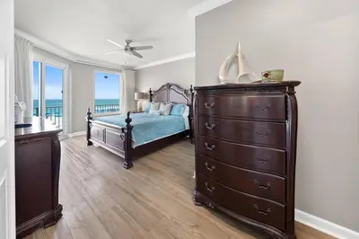a bedroom with a dresser and a bed with the ocean at Grandview East 101 in Panama City Beach