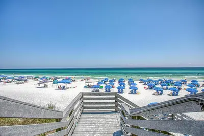 a beach with chairs and umbrellas and the ocean at One Seagrove Place 702 Gulf-front unit sleeps 6 in Santa Rosa Beach