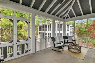 a screened porch with two chairs and a table at Caspian Blue Paradise 30A Luxe Retreat in Seacrest