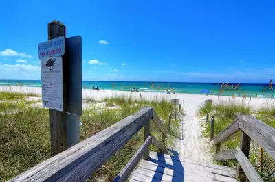 a sign on the beach next to a sandy beach at Destin Towers 1E in Panama City