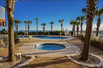 a swimming pool with palm trees and the ocean at Destin Towers 1E in Panama City