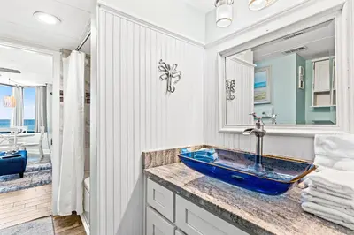 a bathroom with a blue sink and a mirror at Pelican's Perch at the Sunbird in Panama City Beach