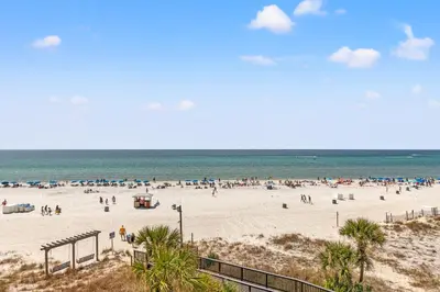 a group of people on a beach near the ocean at Pelican's Perch at the Sunbird in Panama City Beach