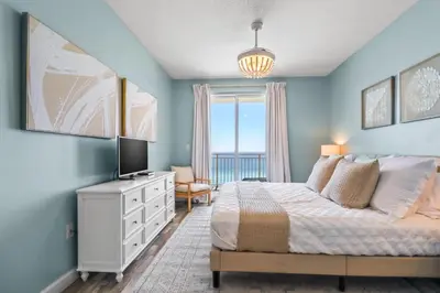 a blue bedroom with a bed and a television at Beach front close to attractions condo- Zenwave Retreat in Panama City Beach