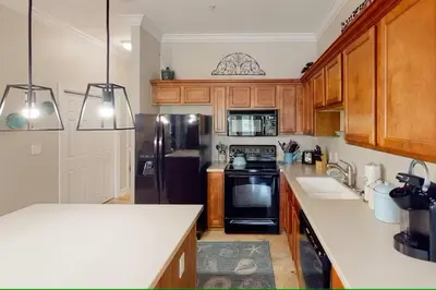 a kitchen with wooden cabinets and a black refrigerator at Seagrove Highlands 1304 in Santa Rosa Beach