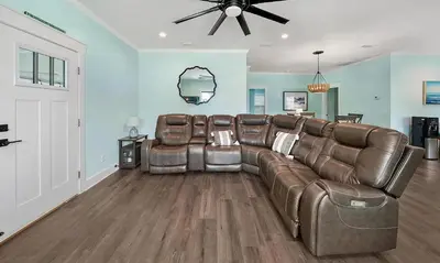 a living room with a leather couch and a ceiling fan at Lah De Dah by Emerald Coast Retreats in Panama City Beach