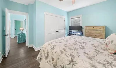 a bedroom with blue walls and a bed with a blanket at Lah De Dah by Emerald Coast Retreats in Panama City Beach