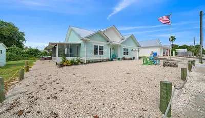 a house on a sandy beach with an american flag at Lah De Dah by Emerald Coast Retreats in Panama City Beach