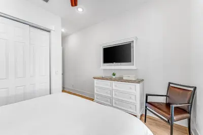 a bedroom with a bed and a tv and a chair at Sand On Tap in Inlet Beach