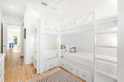 a bedroom with white bunk beds and a hallway at Sand On Tap in Inlet Beach