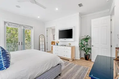 a white bedroom with a bed and a tv at Sand On Tap in Inlet Beach