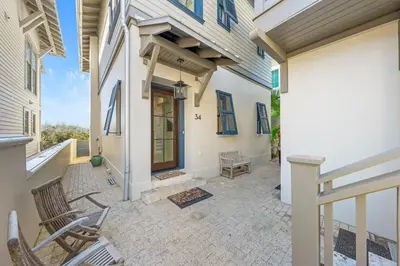 a porch of a house with two chairs at Shell Of A View Cottage And Carriage House in Rosemary Beach
