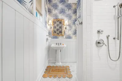 a white bathroom with a sink and a shower at Shell Of A View Cottage And Carriage House in Rosemary Beach