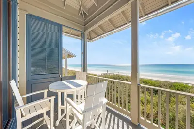 a porch with two chairs and a table with a view of the ocean at Shell Of A View Cottage And Carriage House in Rosemary Beach