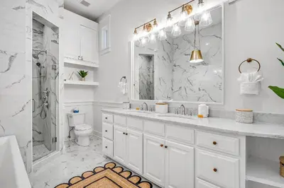 a white bathroom with a shower and a sink at Shell Of A View Cottage And Carriage House in Rosemary Beach