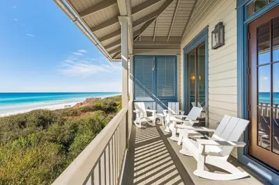 a porch with white chairs and a view of the beach at Shell Of A View Cottage And Carriage House in Rosemary Beach