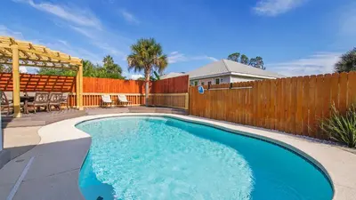 a swimming pool in a backyard with a wooden fence at Guilty Treasure in Panama City Beach