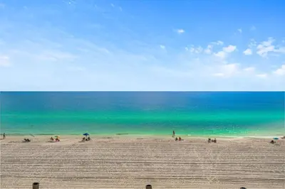 a group of people on a beach with the ocean at Beachfront 3BR Condo! Free Beach Chair Service! by Dolce Vita Getaways PCB! in Panama City Beach