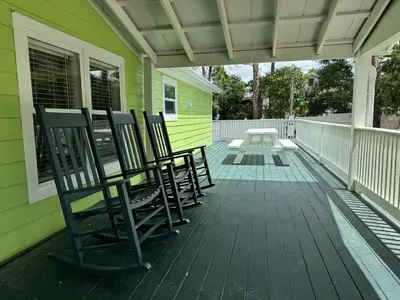 a group of chairs sitting on the porch of a house at R3 Orange at Inlet Beach with Pool, EV Connector and RV Parking in Inlet Beach