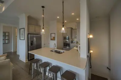 a kitchen with a large island with bar stools at Whale Tales Prominence 30A! BESIDE POOL! 6 seater LSV! 4 Bikes Sleeps 6! in Watersound Beach