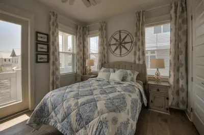 a bedroom with a bed with a blue and white comforter at Whale Tales Prominence 30A! BESIDE POOL! 6 seater LSV! 4 Bikes Sleeps 6! in Watersound Beach