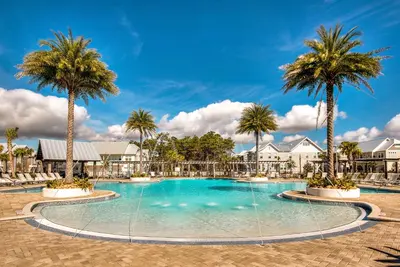 a swimming pool at a resort with palm trees at Whale Tales Prominence 30A! BESIDE POOL! 6 seater LSV! 4 Bikes Sleeps 6! in Watersound Beach