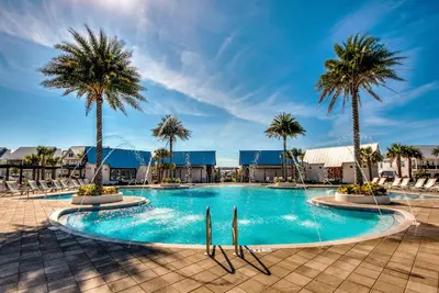 a large swimming pool with palm trees and chairs at Whale Tales Prominence 30A! BESIDE POOL! 6 seater LSV! 4 Bikes Sleeps 6! in Watersound Beach