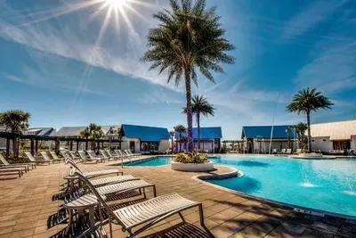 a swimming pool with chairs and a palm tree at Whale Tales Prominence 30A! BESIDE POOL! 6 seater LSV! 4 Bikes Sleeps 6! in Watersound Beach