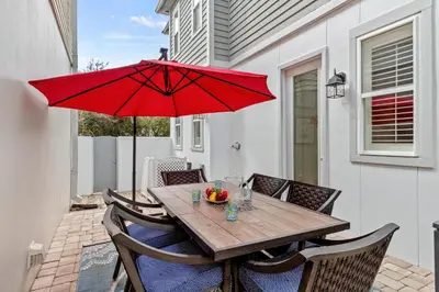 a wooden table with a red umbrella on a patio at Laid Back in Inlet Beach