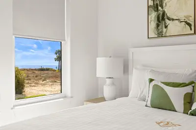 a white bedroom with a bed and a window at The Luxe Lookout in Inlet Beach