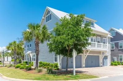 a blue house with palm trees in front of it at Sea - Esta Prominence 30A! BESIDE POOL! 6 seater LSV! 4 Bikes Sleeps 6! in Watersound Beach