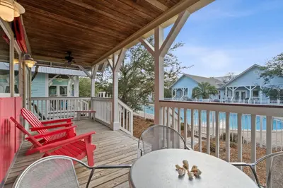 a porch with red chairs and a table at Peacock Cottage in Inlet Beach