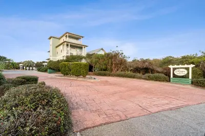 a house with a clock in front of a brick driveway at Peacock Cottage in Inlet Beach