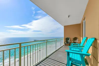 a balcony with two blue chairs and the ocean at Sterling Reef 1404 in Panama City Beach