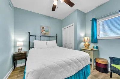 a bedroom with a bed and a chair and a window at Sterling Reef 1404 in Panama City Beach
