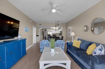 a living room with a blue couch and a table at Calypso 2-2108 West in Panama City Beach