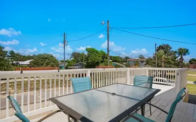 a table and chairs on a deck with a fence at Sand Dollar B by Emerald Coast Retreats in Panama City Beach