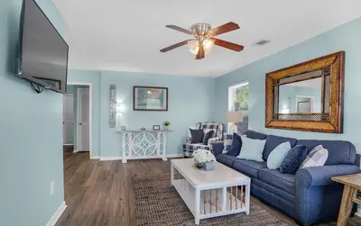 a living room with a blue couch and a ceiling fan at Sand Dollar B by Emerald Coast Retreats in Panama City Beach