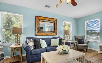 a living room with a blue couch and a mirror at Sand Dollar B by Emerald Coast Retreats in Panama City Beach