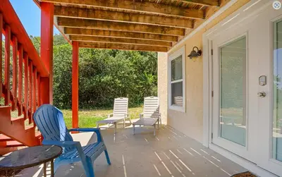 a porch with chairs and a table and a window at Sand Dollar A by Emerald Coast Retreats in Panama City Beach
