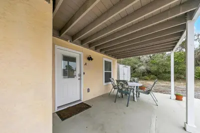 a patio with a table and chairs and a white door at Sand Dollar A by Emerald Coast Retreats in Panama City Beach