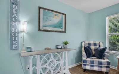a living room with a table and a chair at Sand Dollar by Emerald Coast Retreats in Panama City Beach