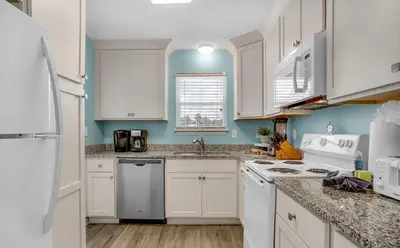 a kitchen with white cabinets and a white refrigerator at Sand Dollar by Emerald Coast Retreats in Panama City Beach