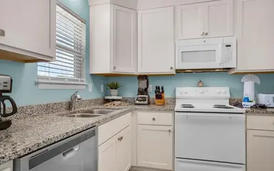 a kitchen with white cabinets and white appliances at Sand Dollar by Emerald Coast Retreats in Panama City Beach