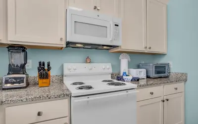a kitchen with white cabinets and a white stove at Sand Dollar by Emerald Coast Retreats in Panama City Beach