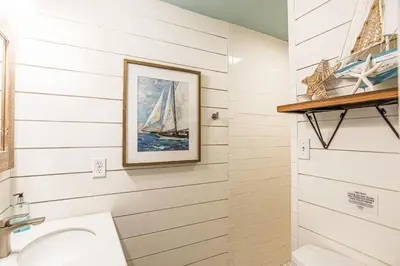 a bathroom with a painting of a sailboat on the wall at A Wave From It All in Laguna Beach Large Patio Sleeps 4 Dog Ok in Panama City Beach