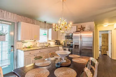 a kitchen with a dining table and a refrigerator at A Wave From It All in Laguna Beach Large Patio Sleeps 4 Dog Ok in Panama City Beach